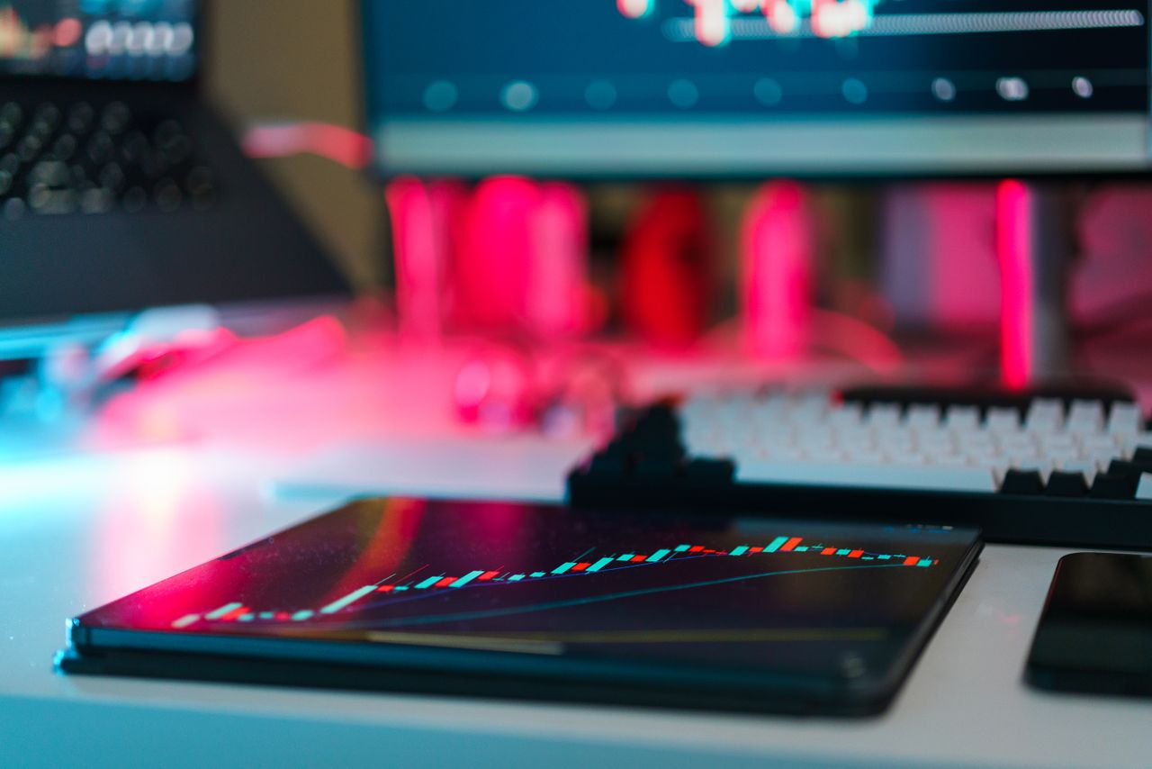 Configuration de trading high-tech avec graphiques sur tablette et écrans d’ordinateur, illustrant l’analyse de données et les tendances financières.